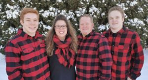 Family in buffalo plaid shirts standing in the snow